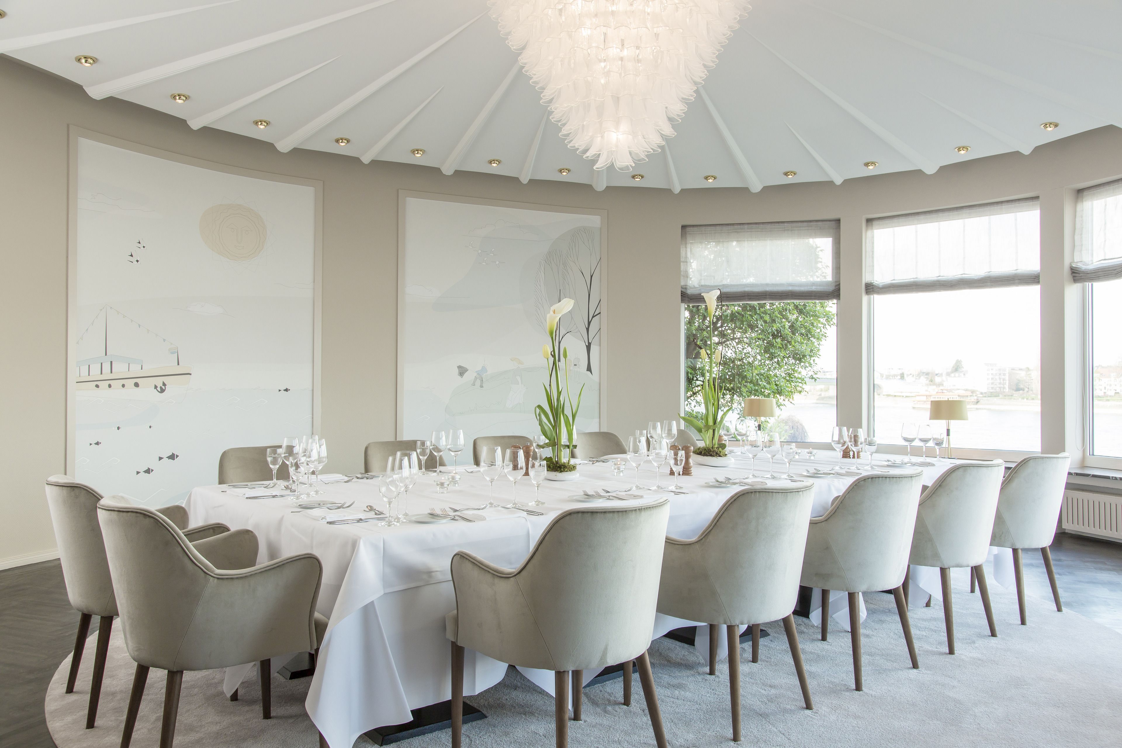 A dining room with a round table set for a meal, surrounded by chairs.