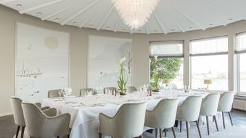 A dining room with a round table set for a meal, surrounded by chairs.