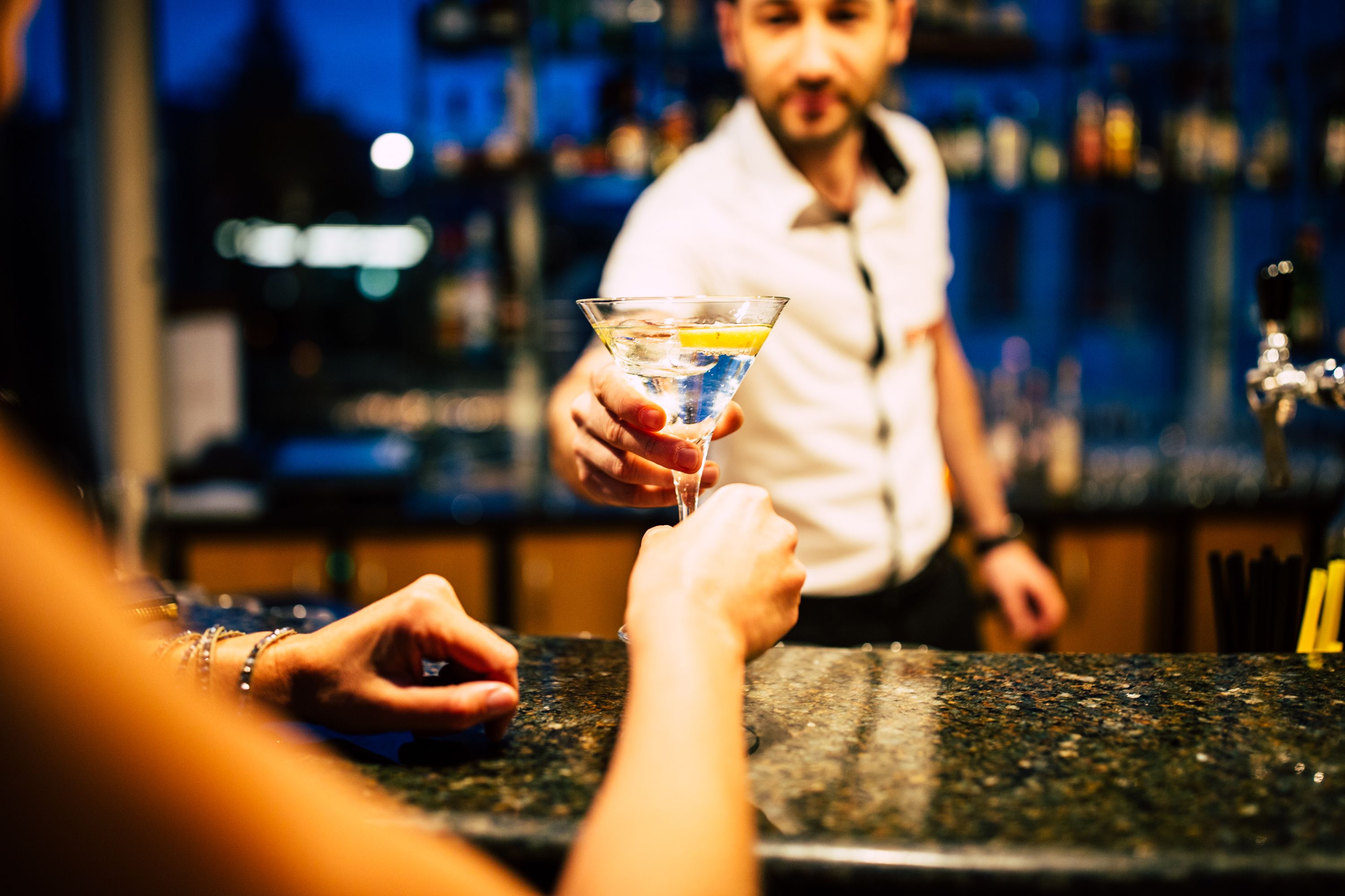 Eine Bar mit einer Person, die ein Martini-Glas hält.