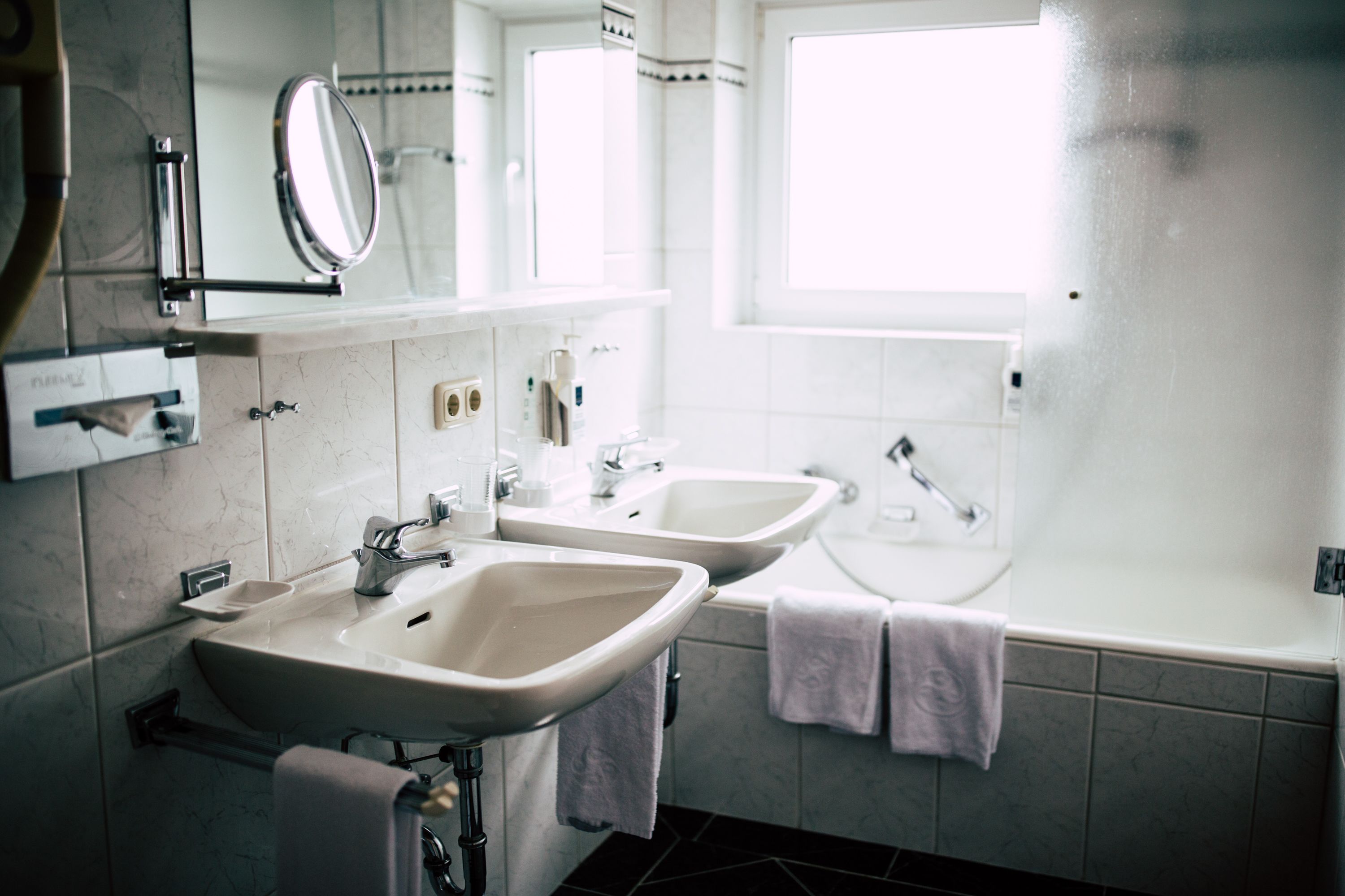 A bathroom with two sinks, a mirror, a window, and a bathtub.