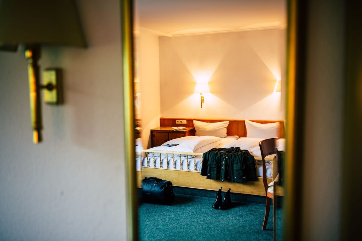A hotel room with a bed, a chair, a nightstand, and a lamp.