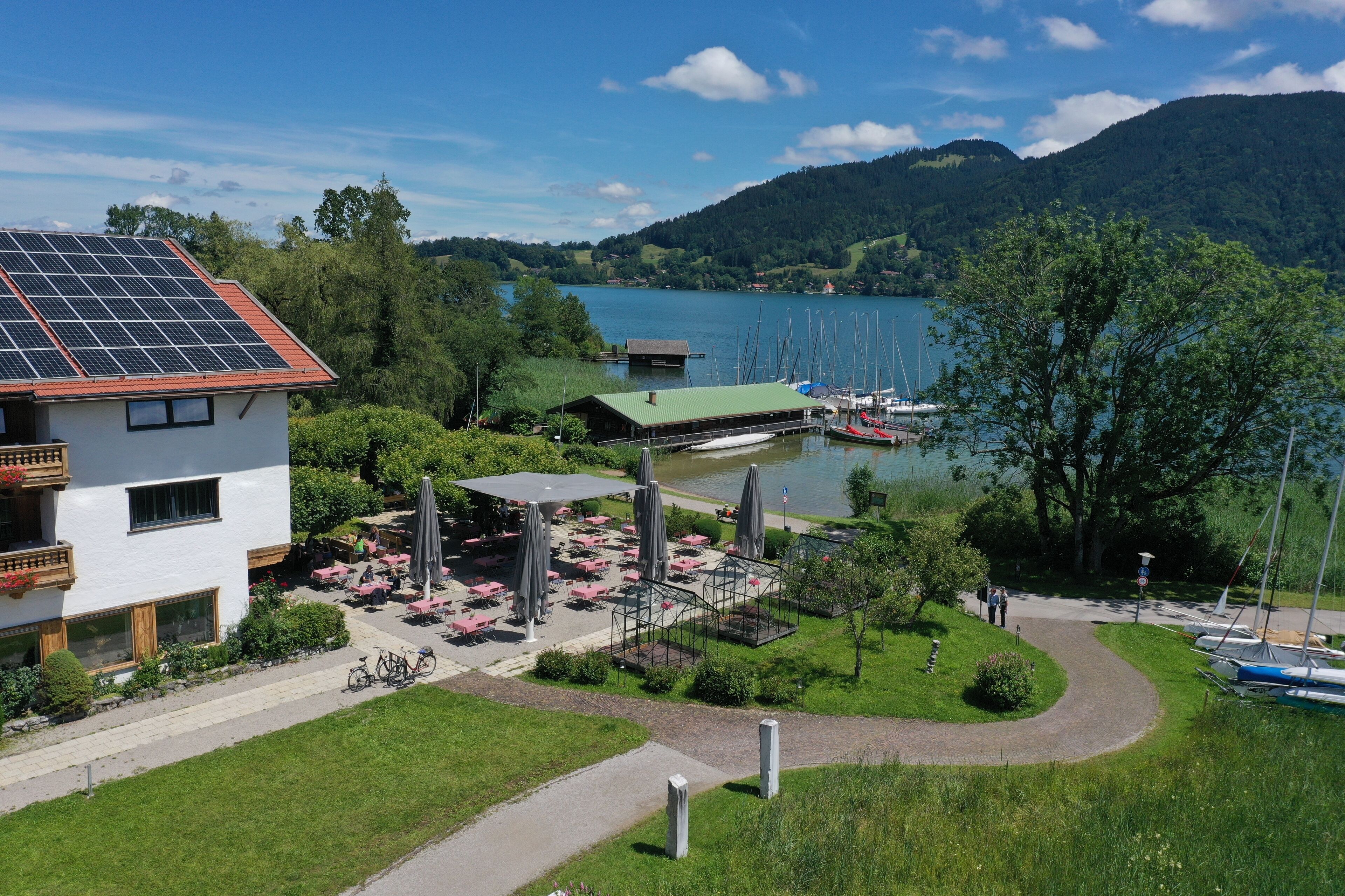 A lakeside hotel with a dining area, outdoor seating, and a view of the lake and mountains.