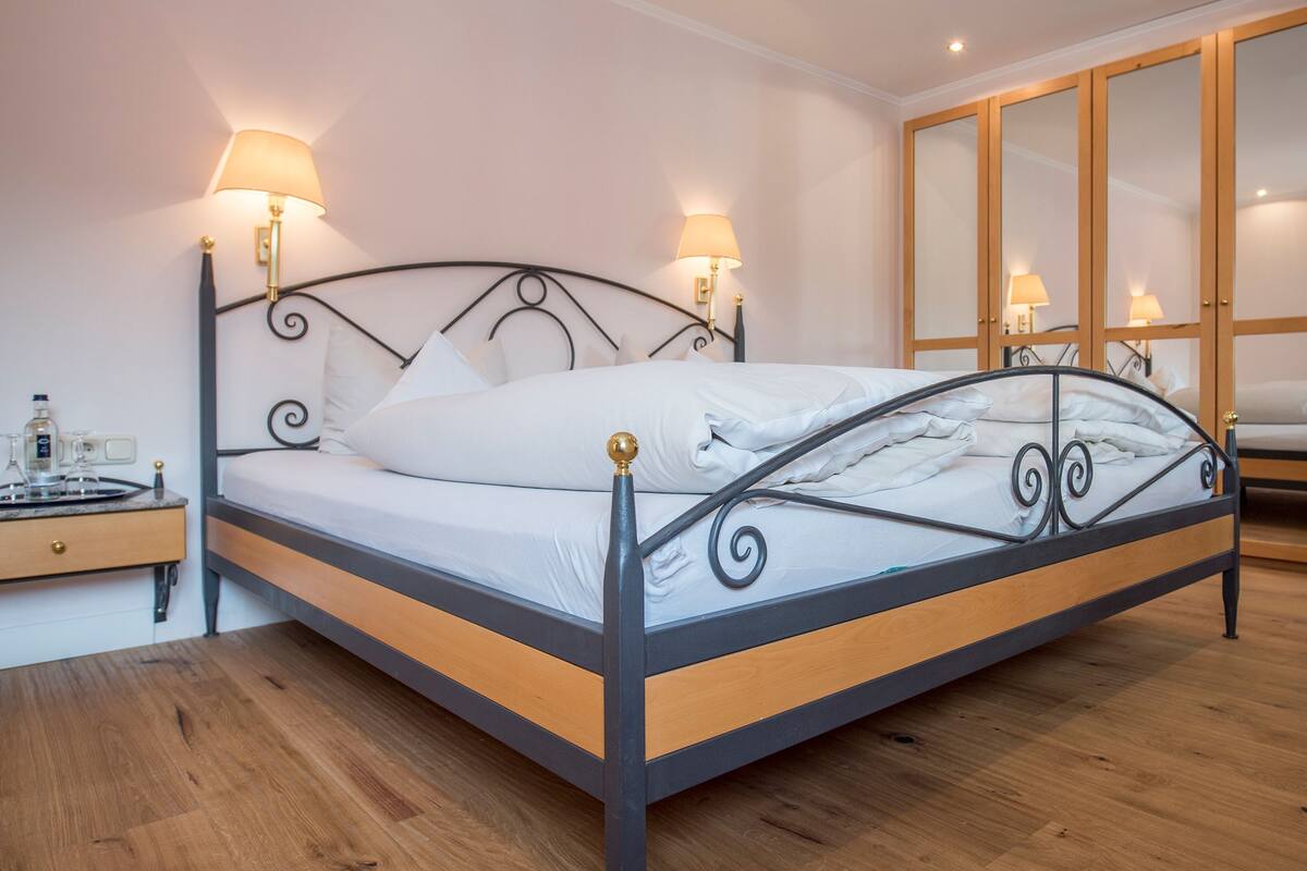 A modern bedroom with a metal-framed bed, wooden floor, and a large mirror cabinet.
