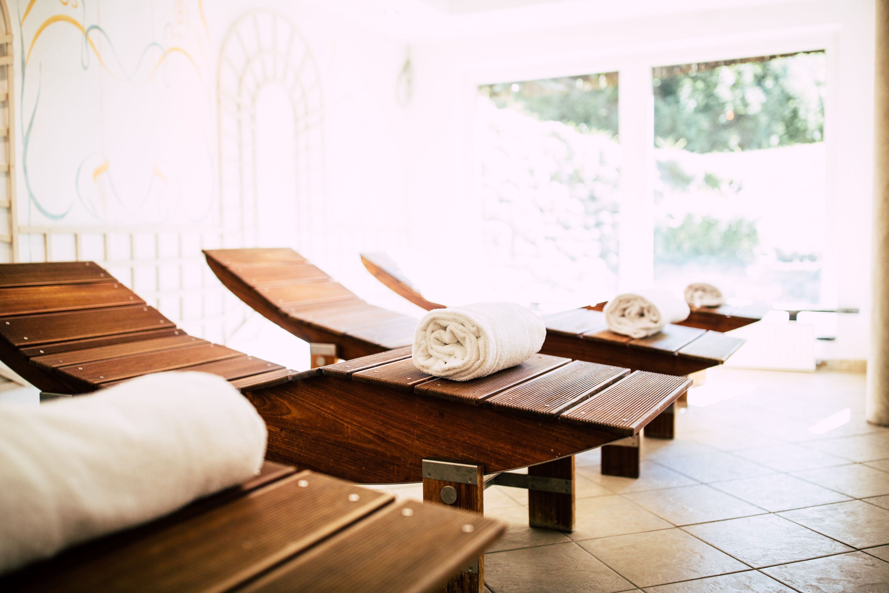Ein Spa-Raum mit Holzliegen, einem Handtuch und Blick auf Grünfläche.