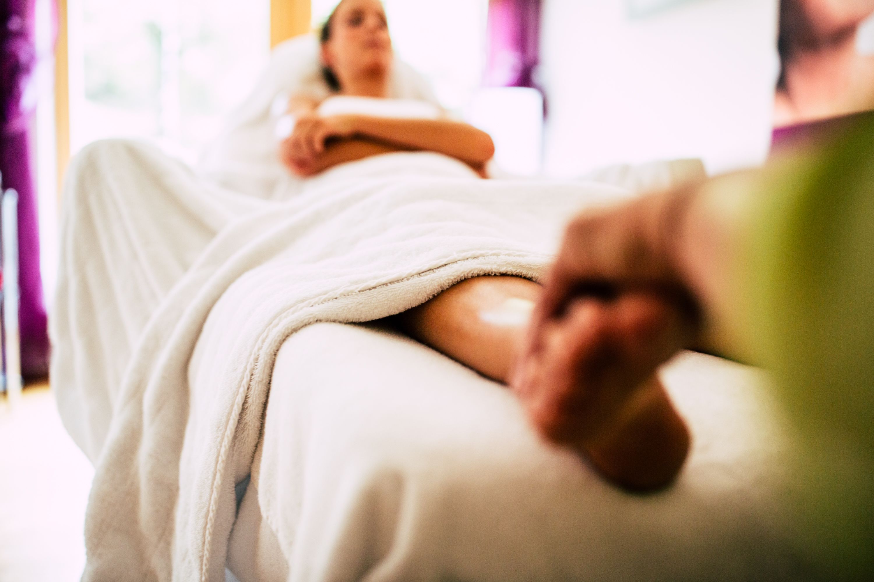 A person lying on a massage table in a spa setting.
