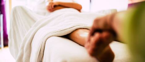 A person lying on a massage table in a spa setting.
