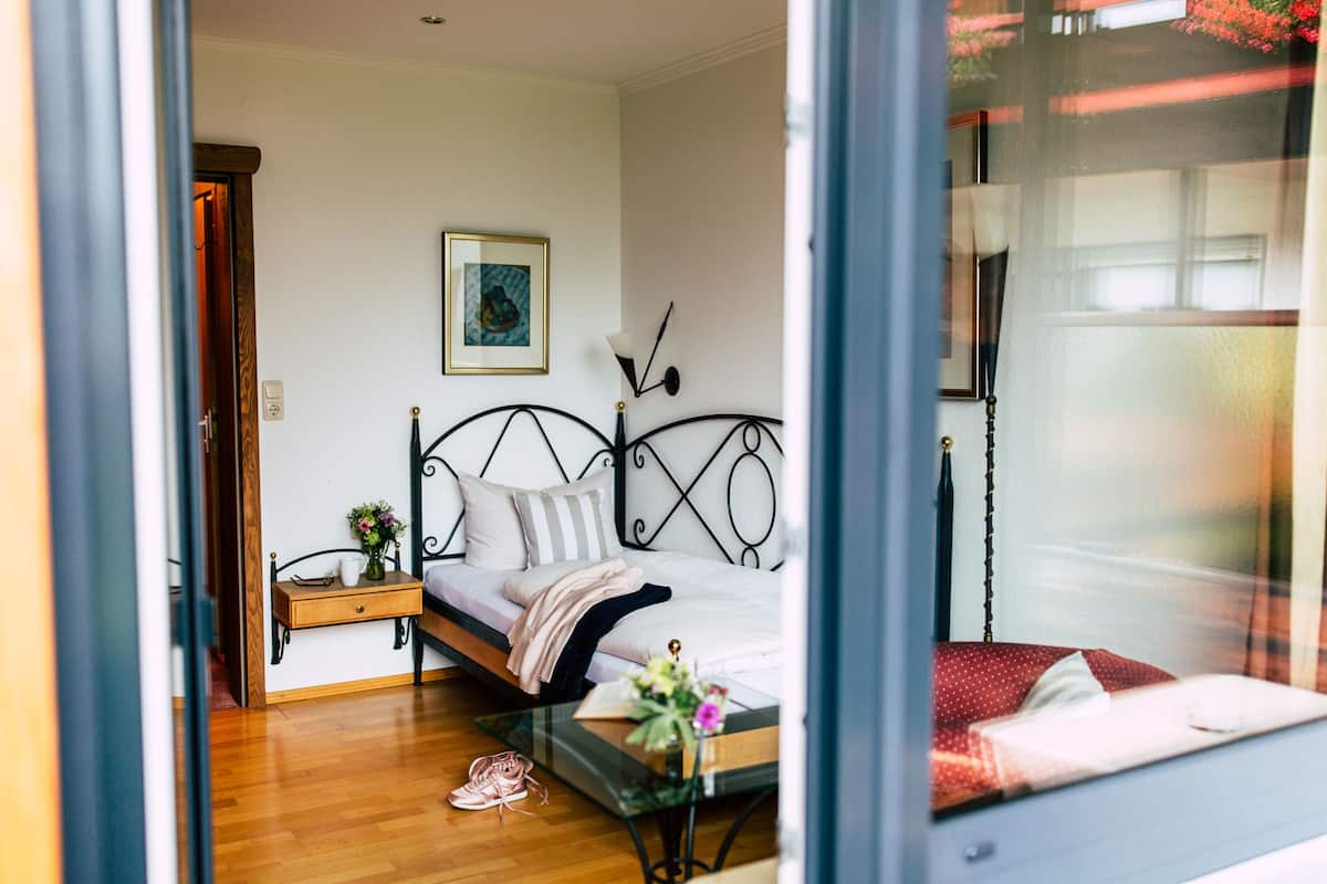 A bedroom with a bed, bedside table, and a window.