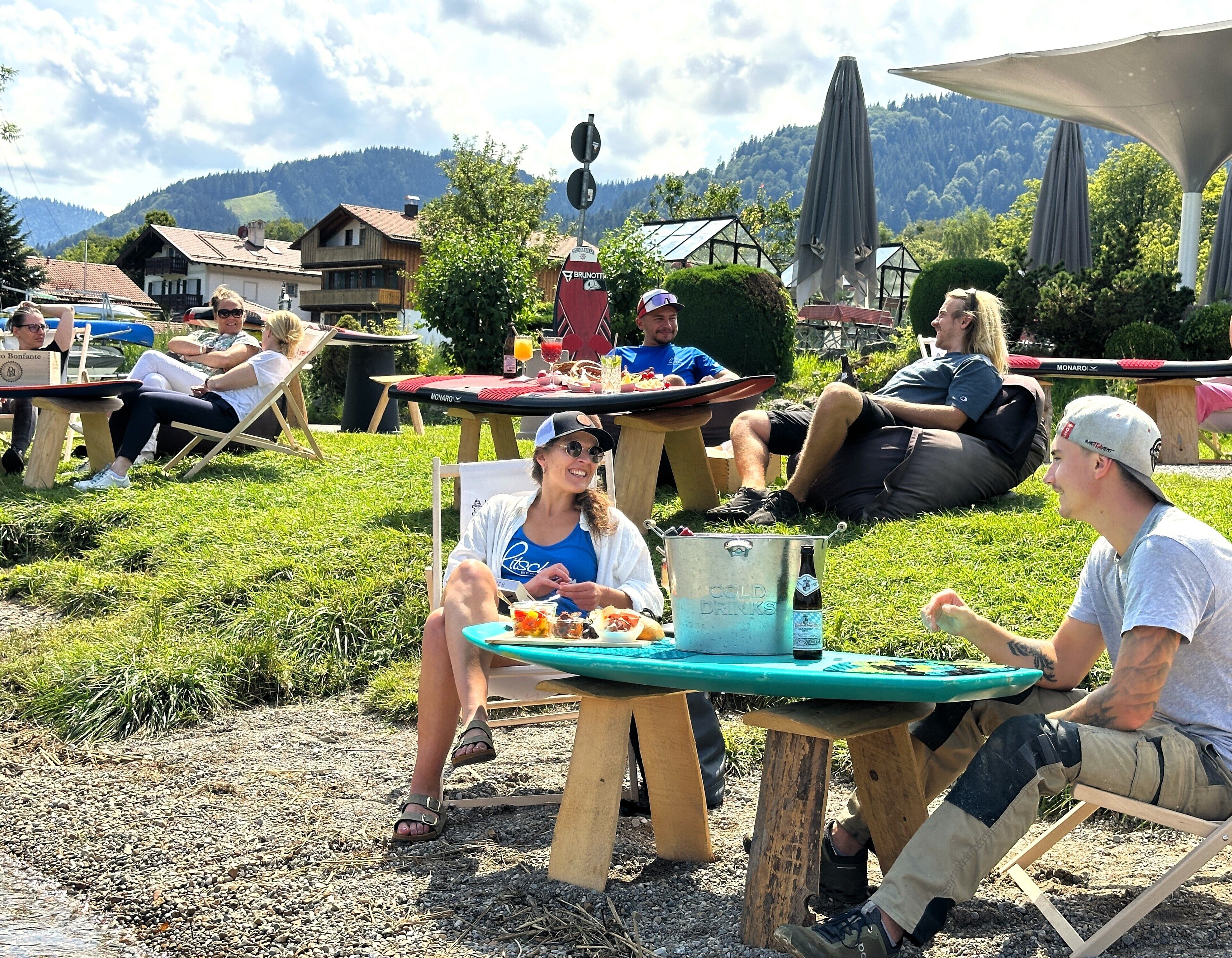 A group of people sitting at tables outdoors with a scenic mountain backdrop.