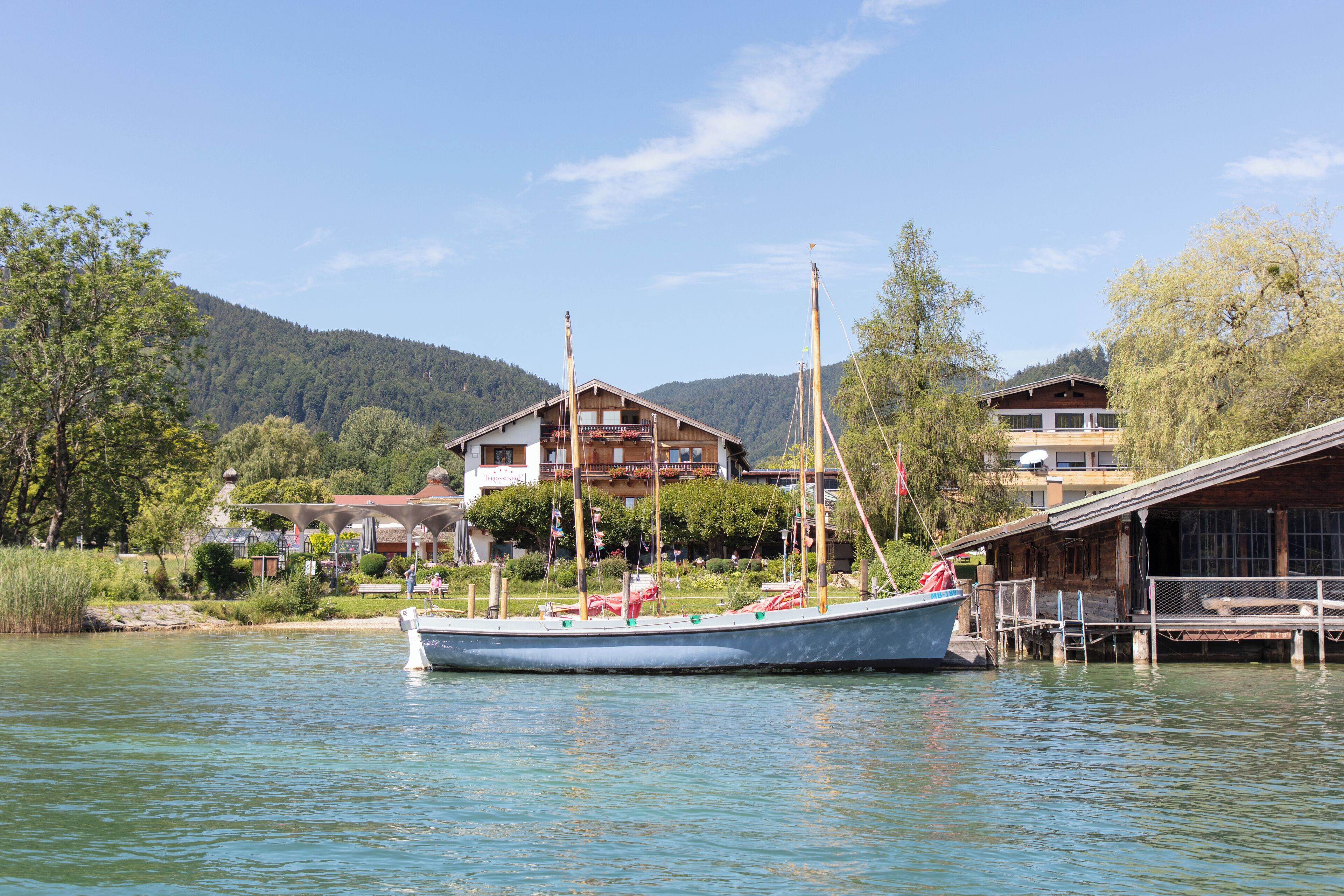 A boat docked at a lakeside property with a wooden cabin and a large house in the background.