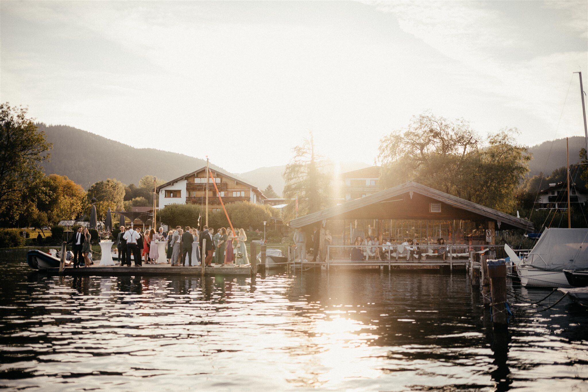 A riverside venue with a dock, boats, and a building with a sloped roof.