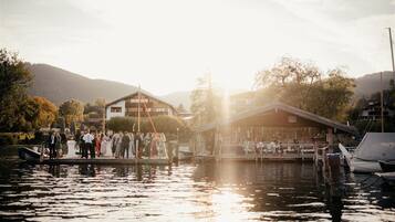 A riverside venue with a dock, boats, and a building with a sloped roof.