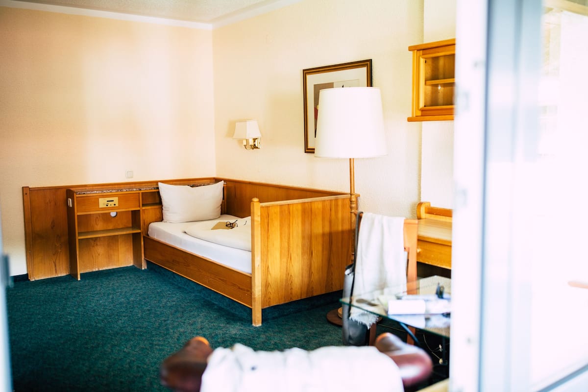 A hotel room with a wooden bed, bedside tables, a lamp, and a mirror on the wall.