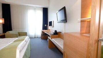 A hotel room with two beds, a desk, a chair, a television, and a window with curtains.