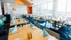 Een moderne eetruimte met gedekte tafels, grote ramen en uitzicht op de stadslijn.