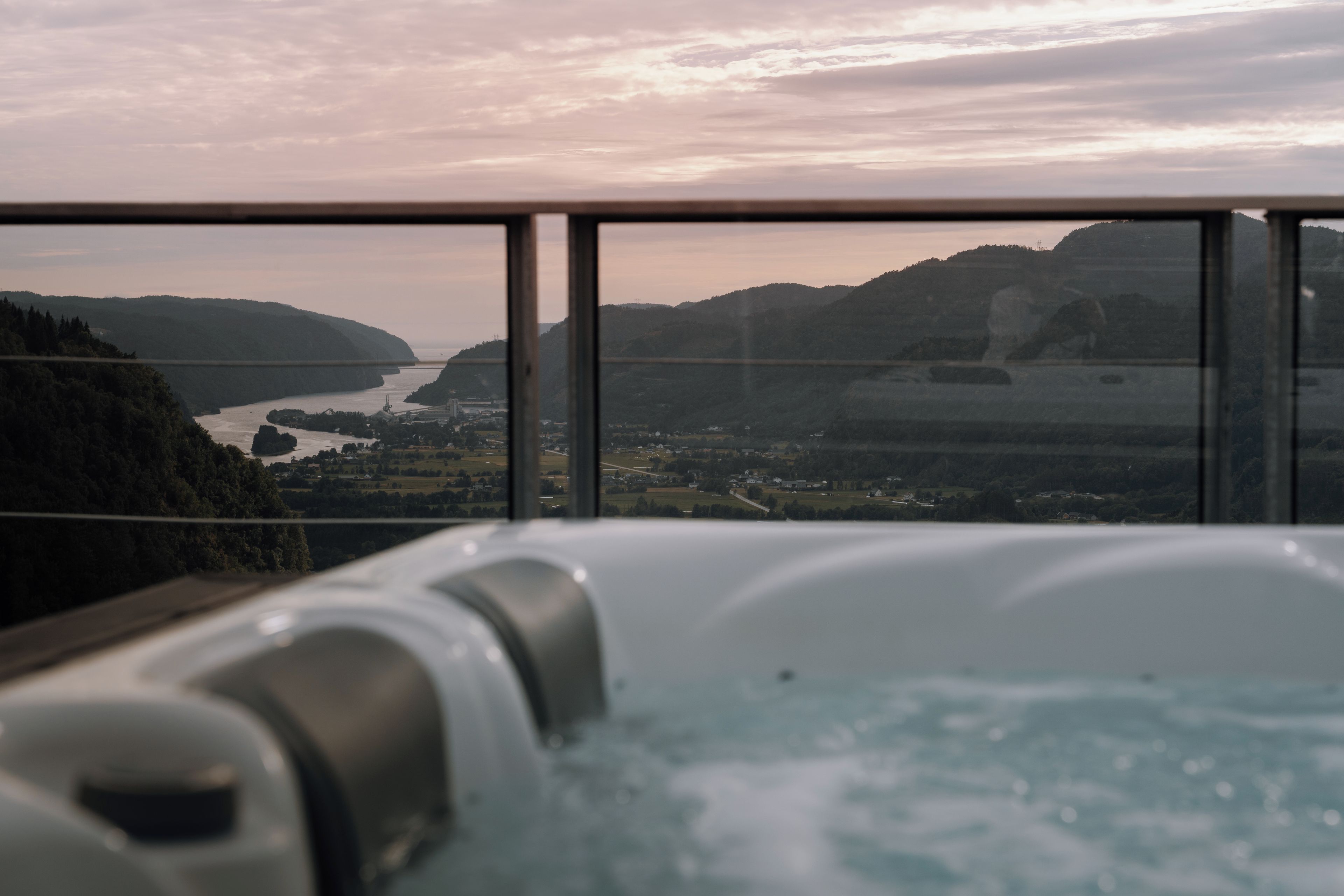A hot tub with a view of a river and hills.