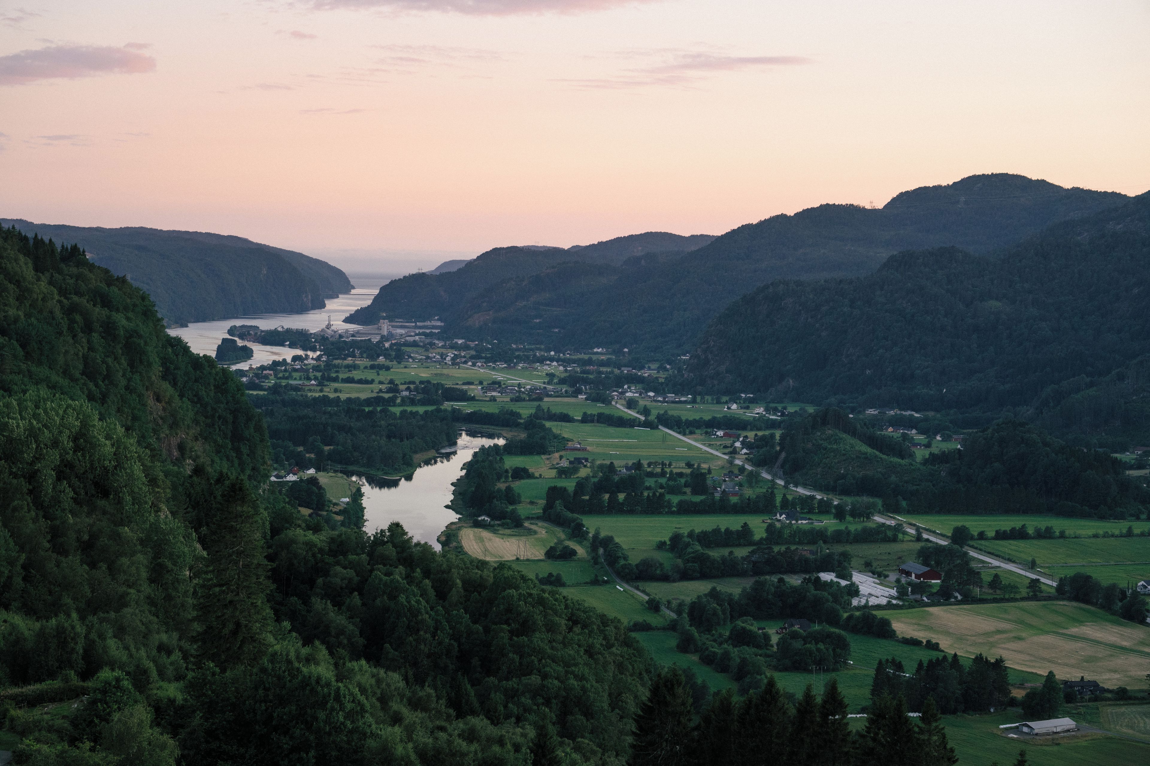Vista panorâmica de um vale com um rio, rodeado por colinas e vegetação.