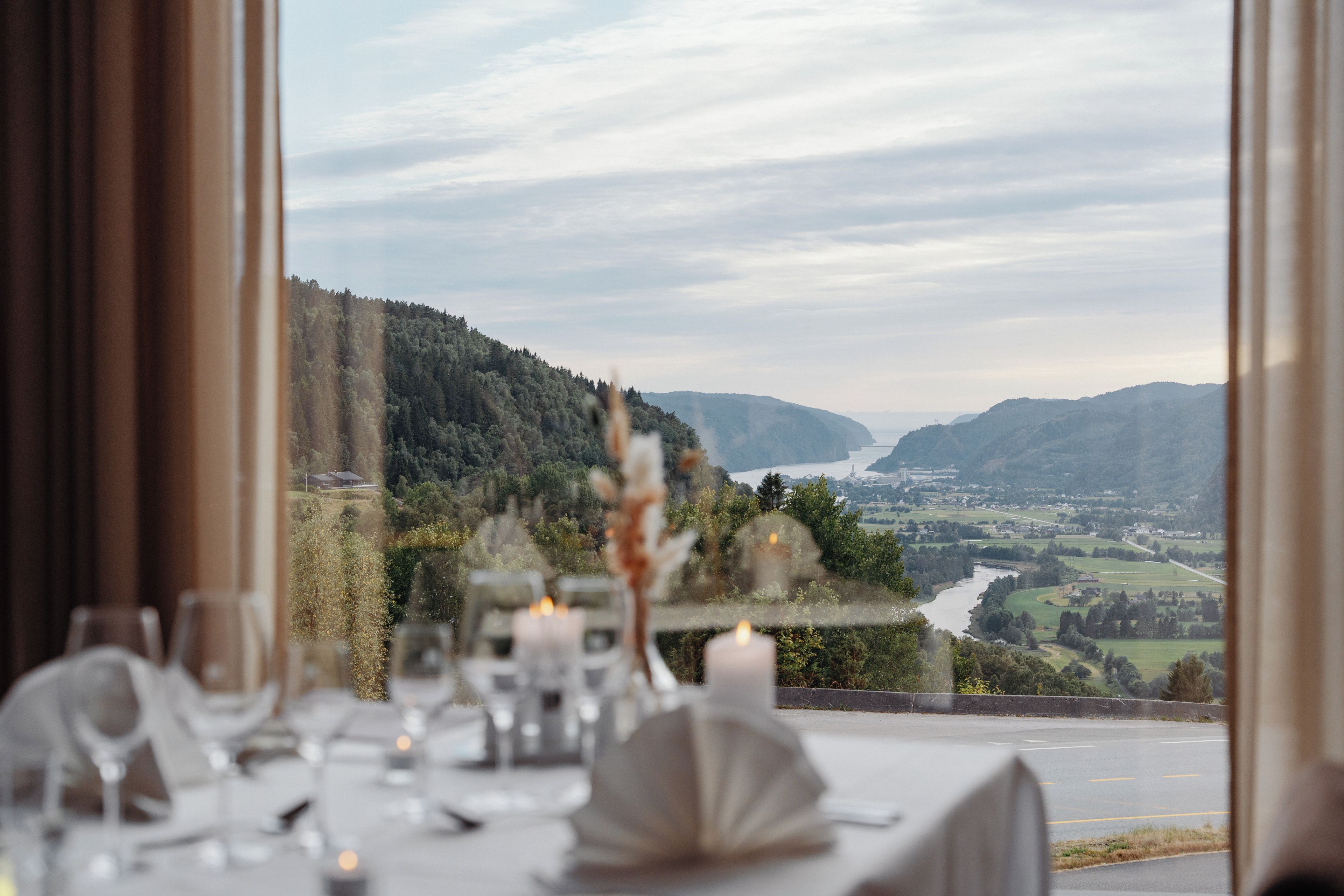 A table set for dining with a view of a valley and mountains.