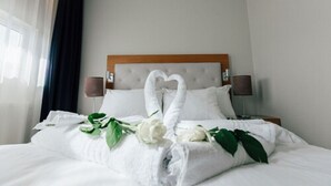 Een hotelkamer met een bed, witte handdoeken en een handdoekarrangement in de vorm van een hart.