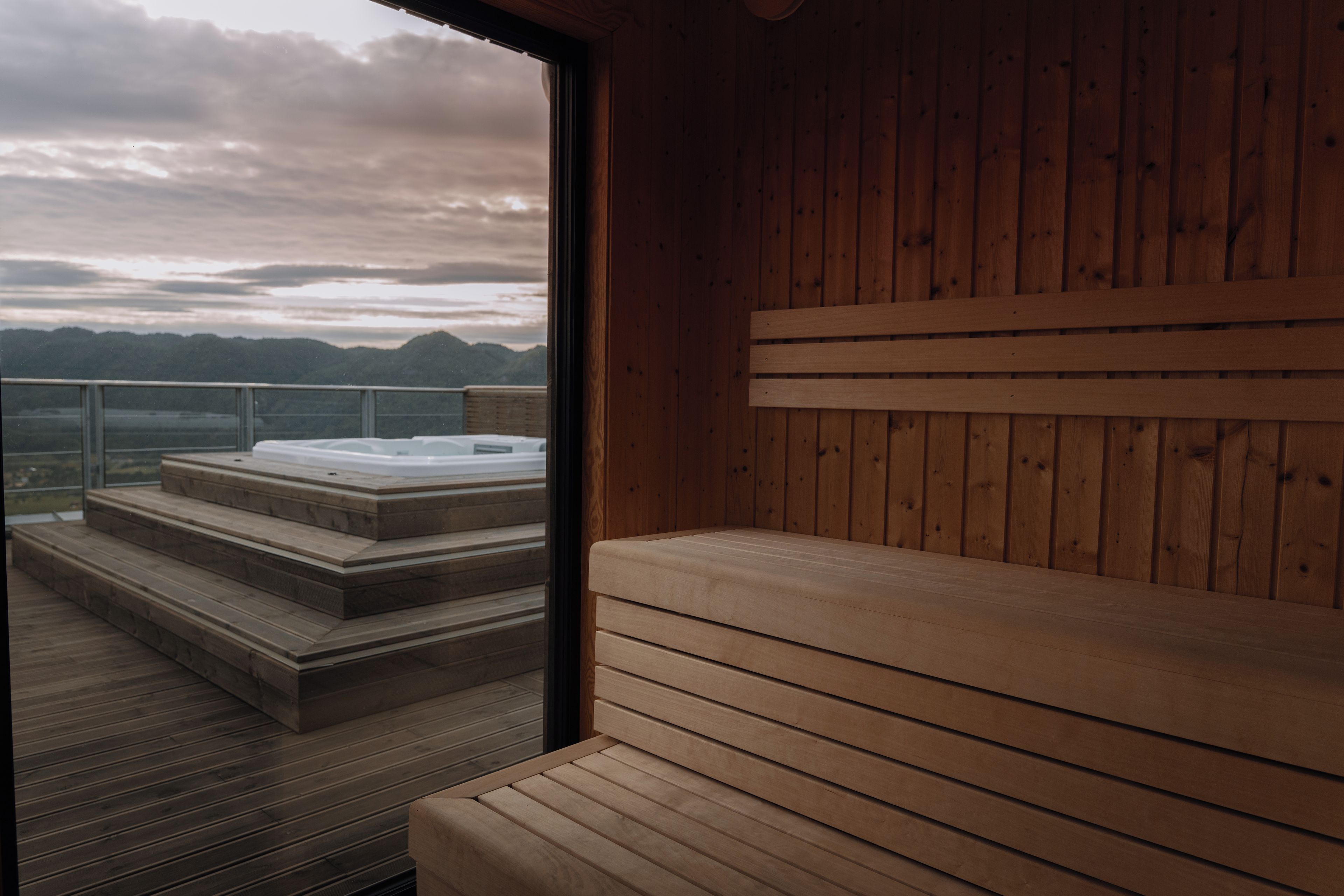 Eine Holzsauna mit Sitzbank und Treufen, die zu einem Whirlpool führen.