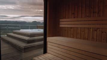 Una sauna de madera con un banco y escalones que llevan a un jacuzzi.