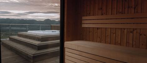 Eine Holzsauna mit Sitzbank und Treufen, die zu einem Whirlpool führen.