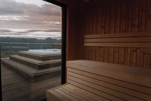 Una sauna de madera con un banco y escalones que llevan a un jacuzzi.