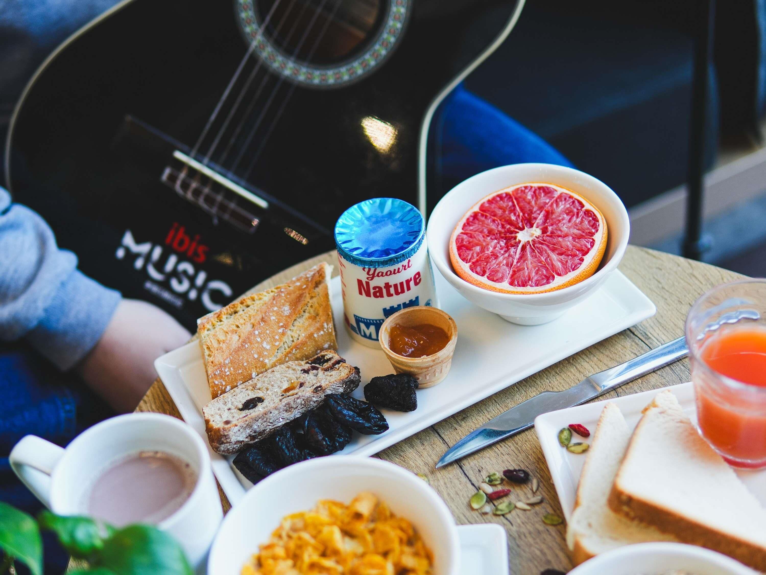 Un desayuno con pan, pomelo, mermelada y un envase de yogur.