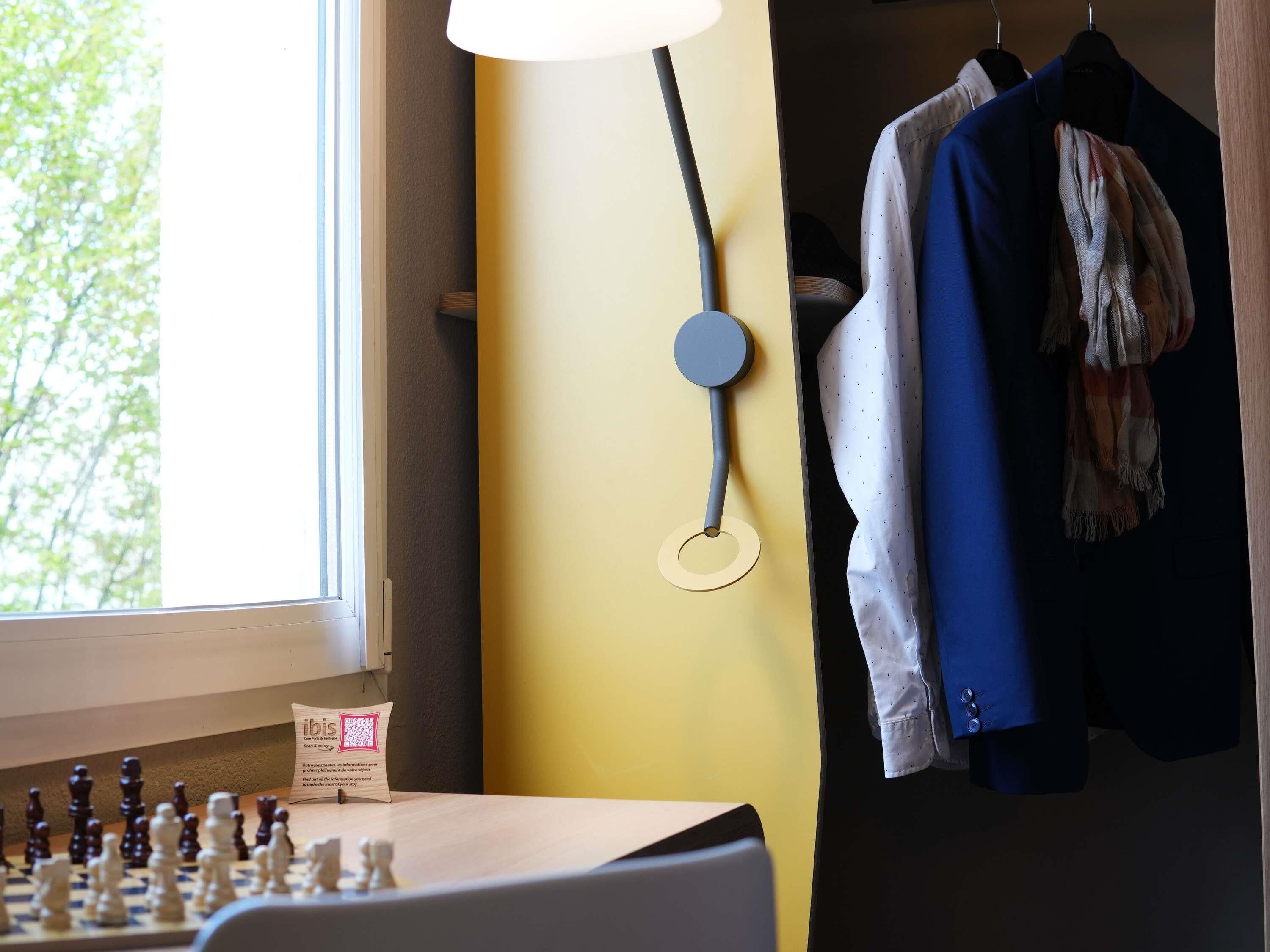 Ein Schachbrett, eine Lampe und aufgehängte Kleidung.