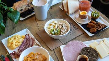 A breakfast table with various food items, including eggs, bacon, cereal, toast, and a glass of juice.