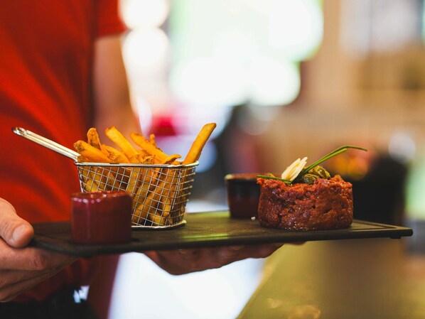 A tray with fries, a small bowl of sauce, and a meat dish.