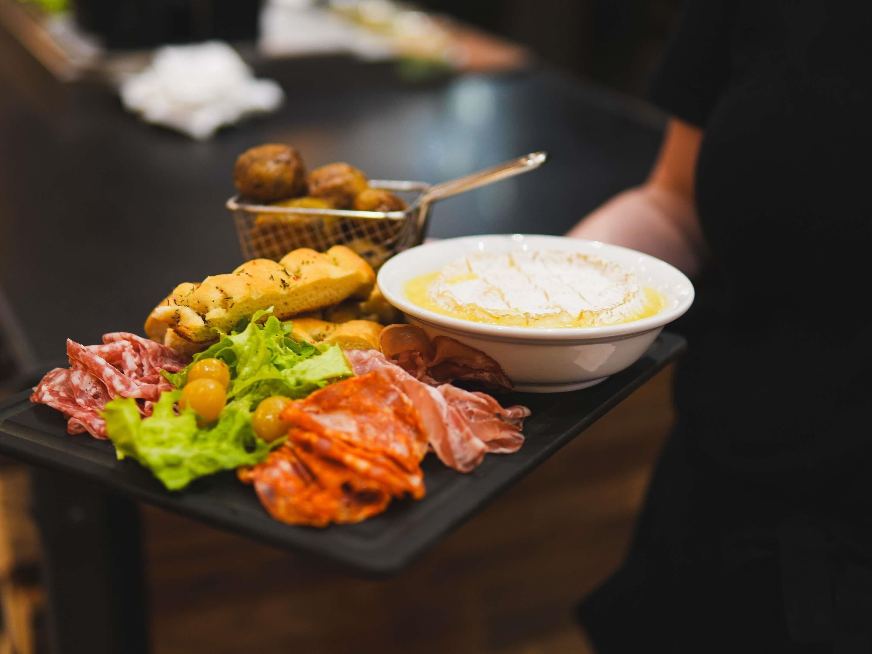 A tray with various food items including bread, cheese, meats, and olives.