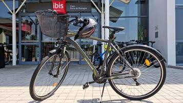 Ein Fahrrad vor einem Gebäude mit der Aufschrift 'ibis Hotels Caen Porte de Bretagne'.