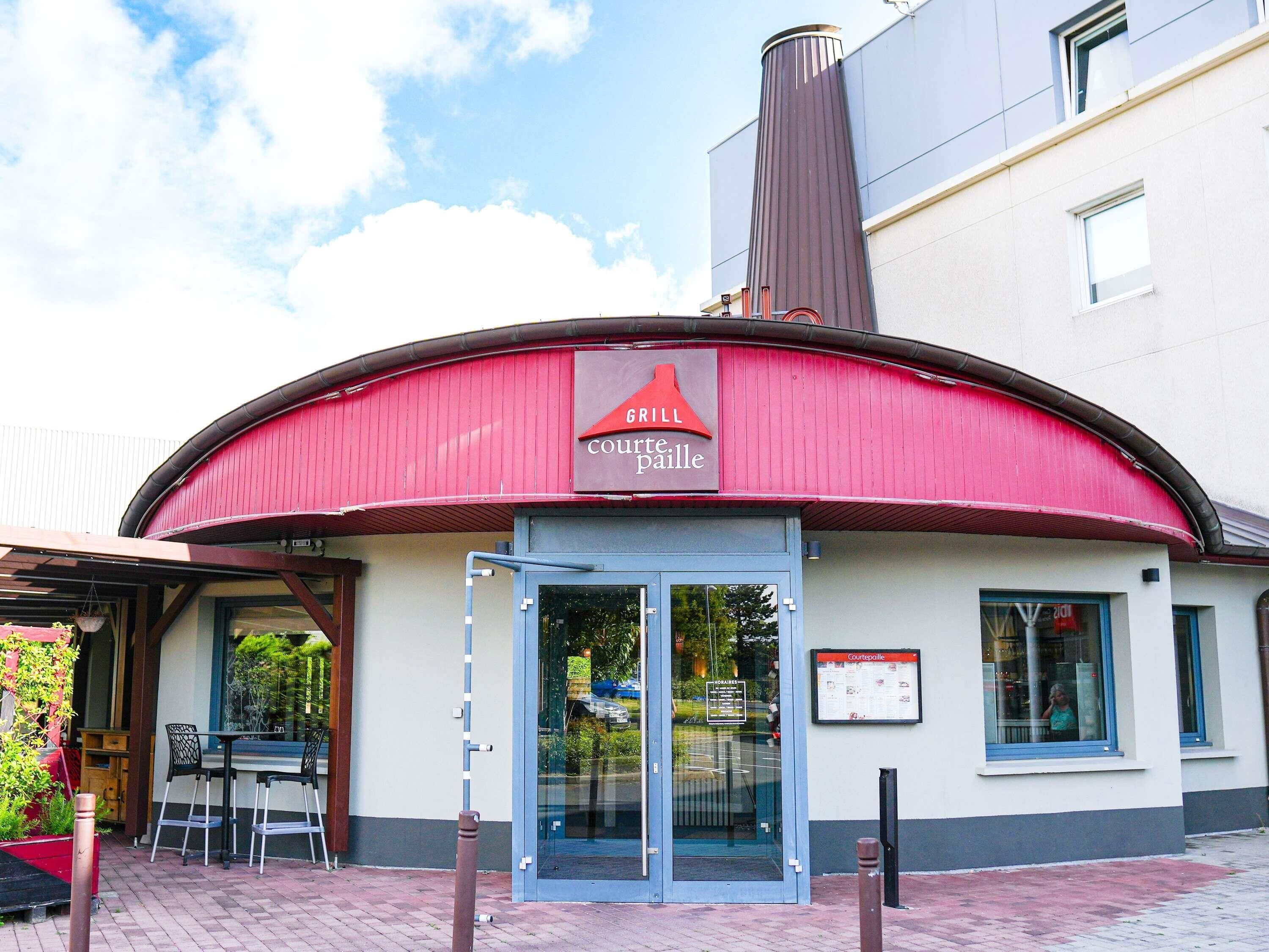 Een restaurant met een rood luifel, een glazen deur en een bordje waarop 'GRILL courte paille' staat.