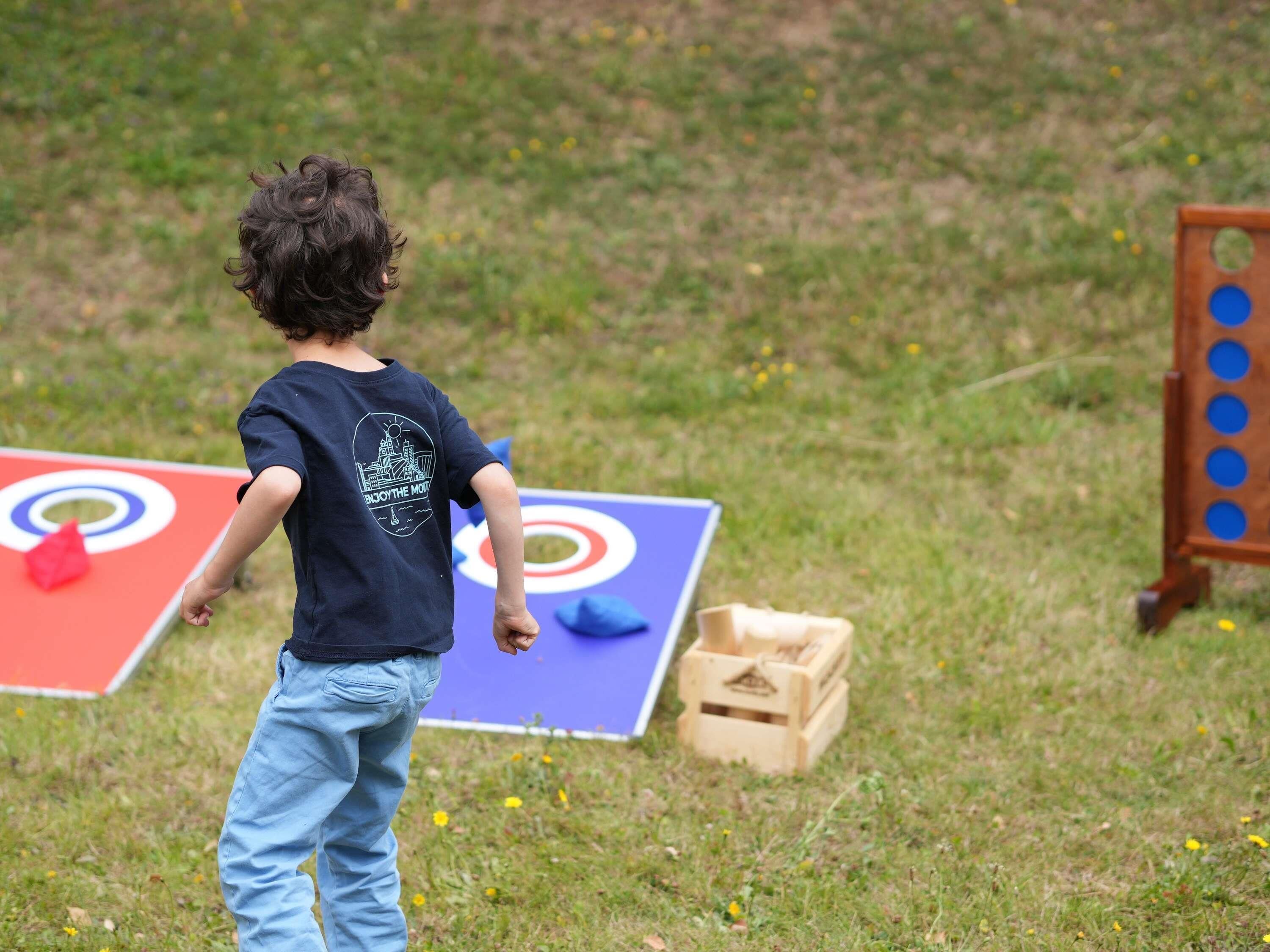 A child playing with a ball on a grassy field with a target board.