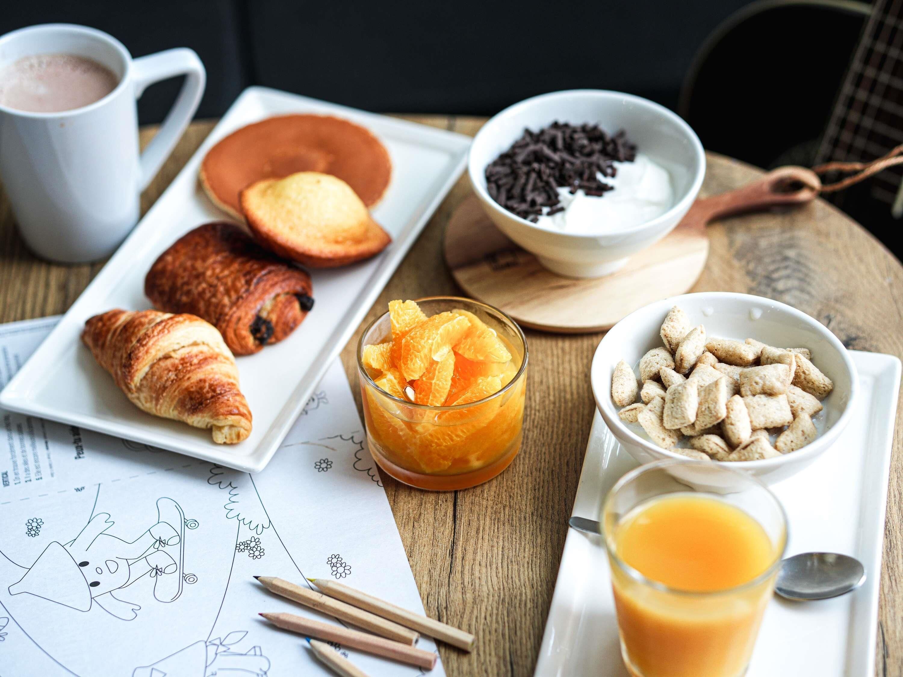 A breakfast setting with croissants, orange juice, and cereal.