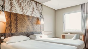 A hotel room with two beds, a large window, and a marble-patterned headboard.