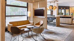Un área de estar moderna con un sofá, sillas, un televisor y una mesa de recepción.