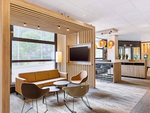 Un área de estar moderna con un sofá, sillas, un televisor y una mesa de recepción.