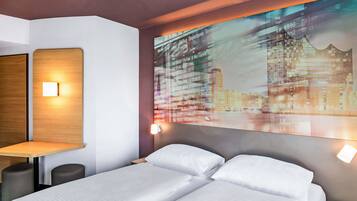 Ein modernes Hotelzimmer mit Bett, Nachttischen, Schreibtisch und einem an der Wand befestigten Fernseher, der Fluginformationen anzeigt.