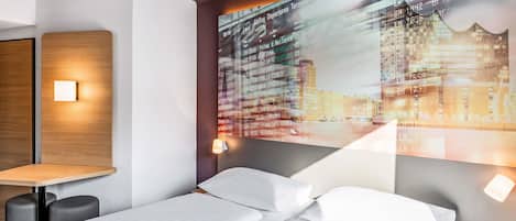 Habitación de hotel con cama, mesitas de noche y una pantalla en la pared mostrando información de vuelos.