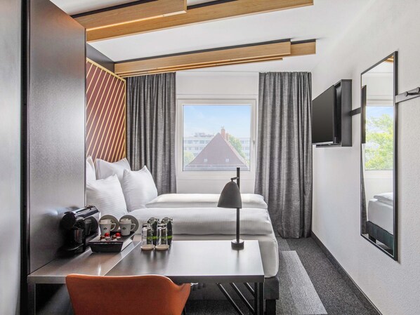 A hotel room with a bed, a desk with a chair, a coffee maker, and a TV mounted on the wall. - B&B HOTEL Hamburg-Airport (Hamburg)