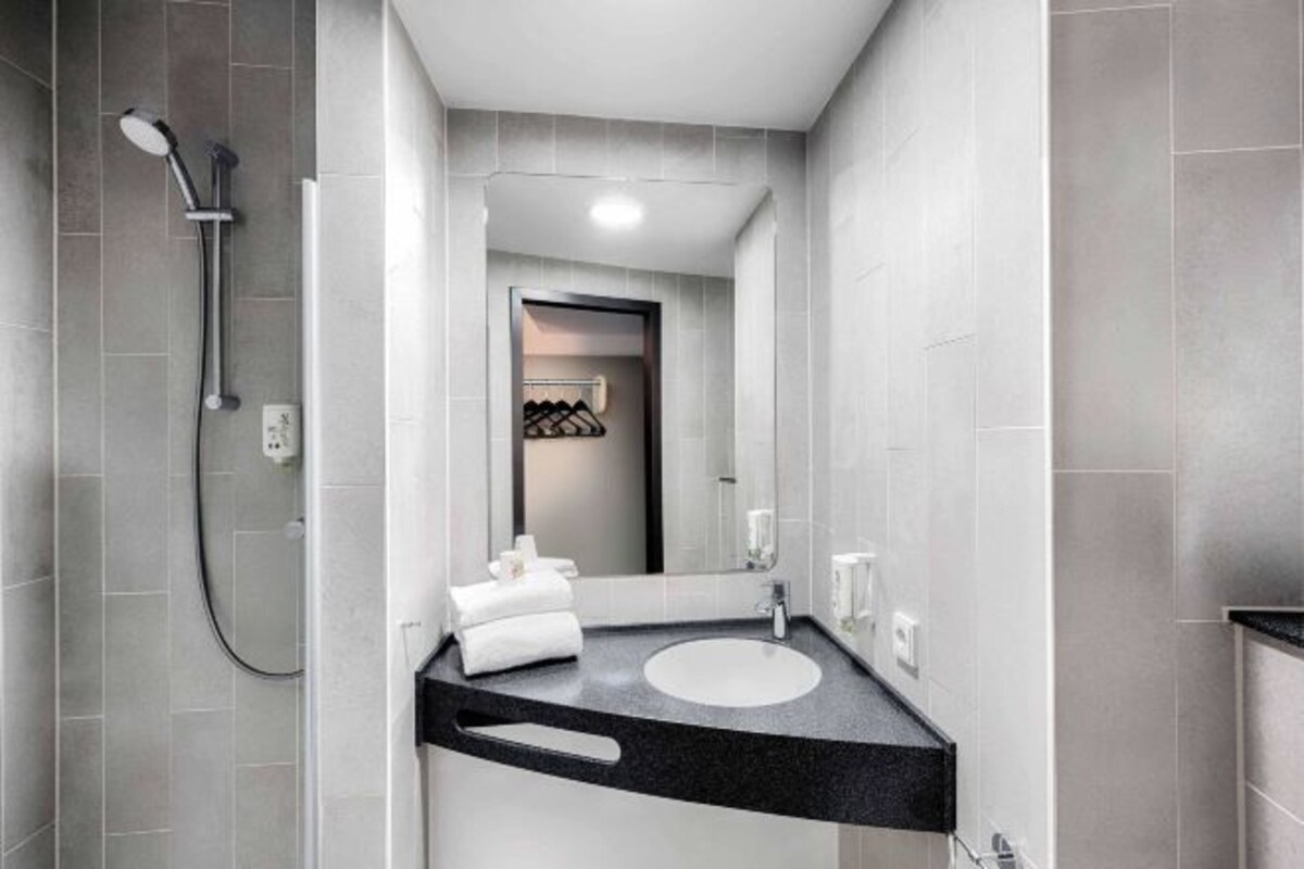 Un baño moderno con ducha, lavamanos y espejo.