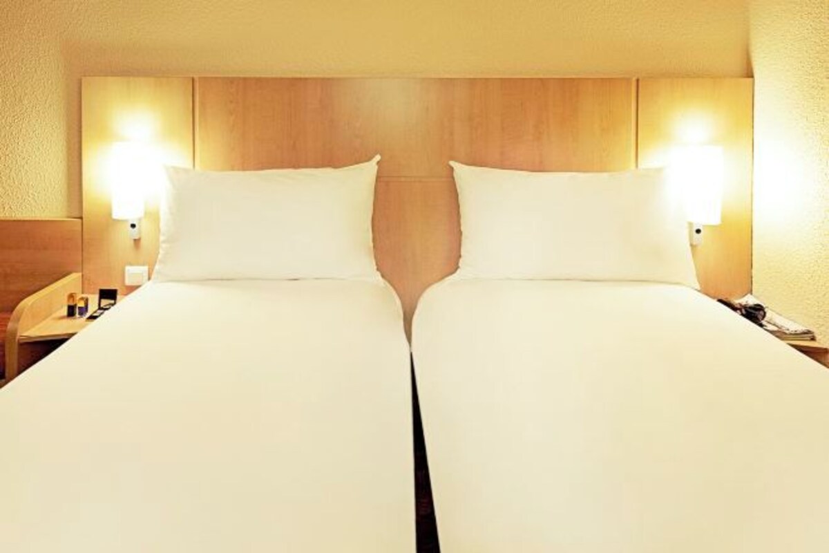Una cama doble con dos mesitas de noche, cada una con una lámpara.