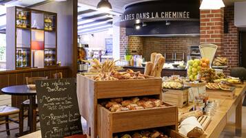 Un comptoir de boulangerie avec du pain et des pâtisseries, un menu écrit à la craie et une pancarte indiquant : « GRILLADES AU FEU DE CHEMINEE ».