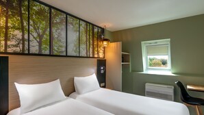 Een hotelkamer met een groot bed, een bureau, een stoel, een raam en een kunstwerk aan de muur.