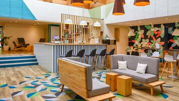 A modern lounge area with a bar, seating arrangements, and a colorful abstract wall.