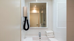 Een moderne badkamer met een witte wastafel, een spiegel, een handdoekrek en een douchecabine van glas.