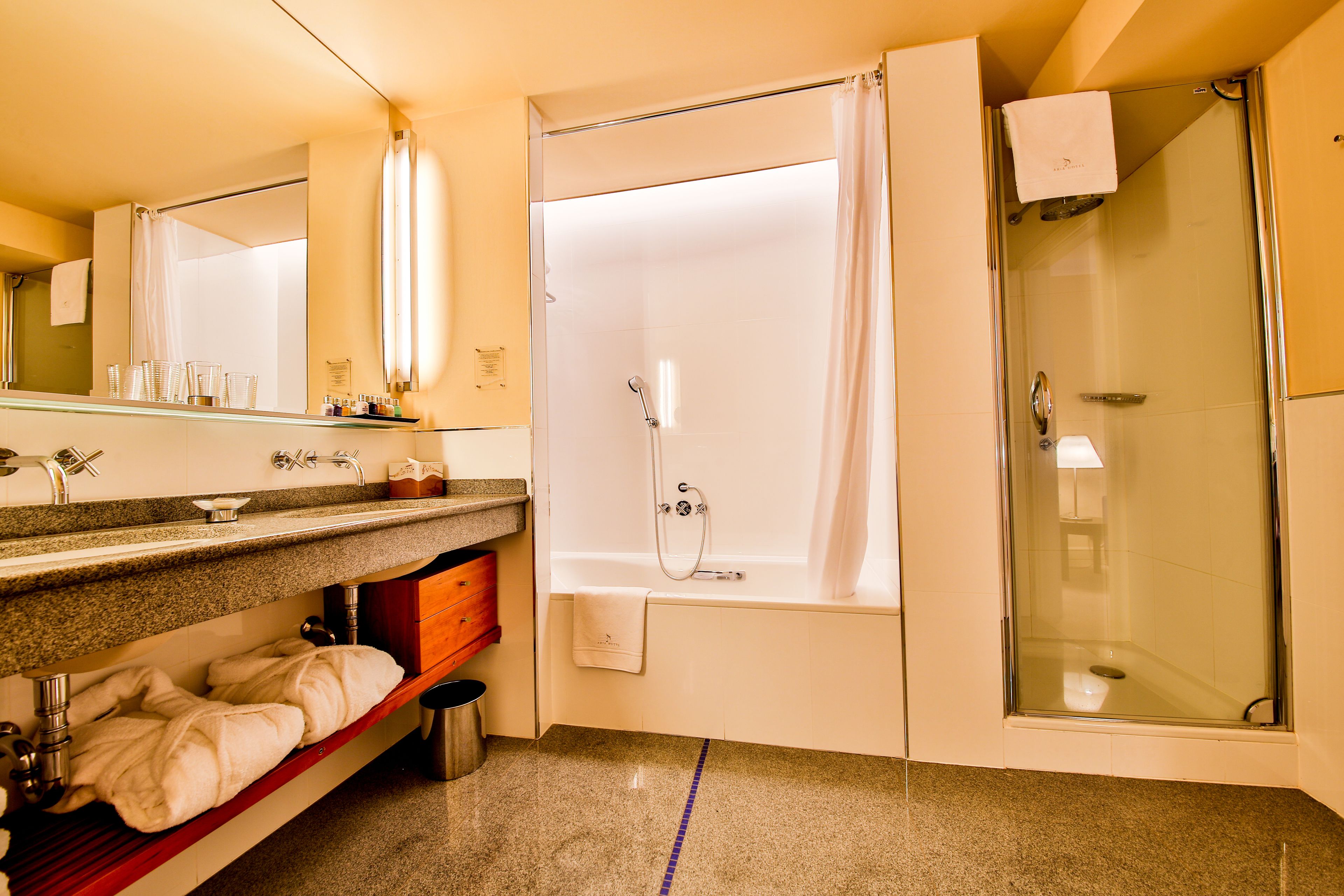A modern bathroom with a glass-enclosed shower, a bathtub, and a vanity with a mirror and countertop.