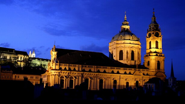A historic building with a prominent dome and adjacent clock tower, surrounded by other structures. - Aria Hotel Prague (Prague)