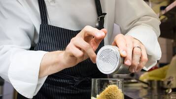 Un chef preparando un plato con un rallador y un vaso de líquido.